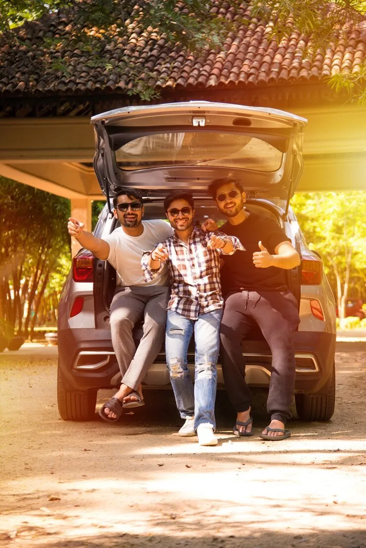Friends enjoying a trip with Monthly Car Rental in Dhaka, sitting by the car and smiling for a fun travel experience.
